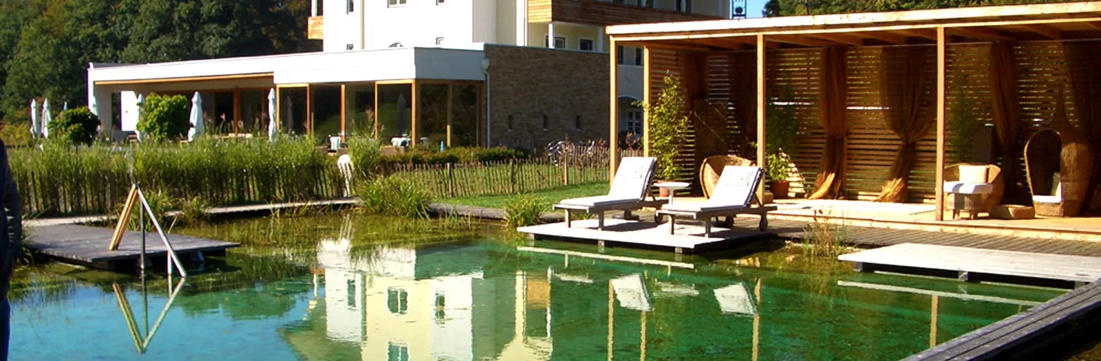 Großer Naturpool mit Holzdeck, Liegen und Holzpavillon